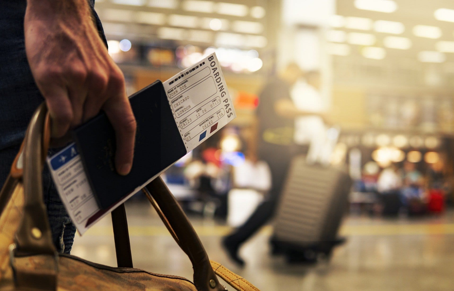 Hand hält Reisepass und Bordkarte, gehend im Flughafen. Hintergrund unscharfe Reisende und Gepäckwagen. Bordkarte zeigt "London" und "Chicago".