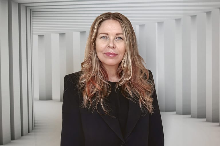 Darstellung von Lisa Hembree, die leicht zur Seite blickt und lächelt, vor einem Studiohintergrund in gedeckten Farben.