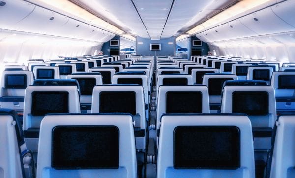 Innenansicht eines Flugzeuges mit mehreren Reihen von Sitzen, ausgestattet mit Bildschirmen an den Kopfstützen.