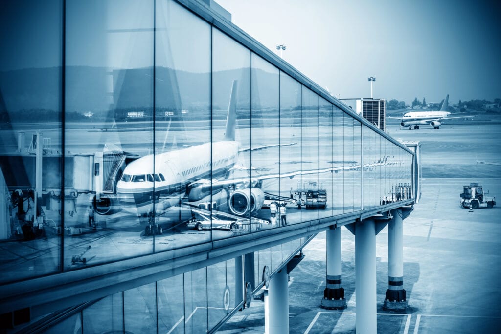 A plane is parked at an airport terminal, surrounded by passengers and luggage carts.