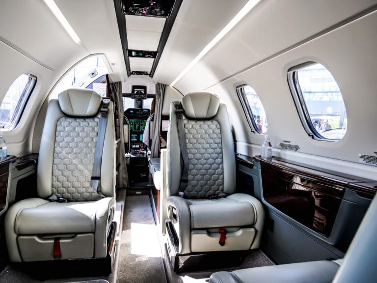 Interior view of a private jet showcasing spacious leather seats designed for a premium travel experience. Phenom 300 E | PASflights