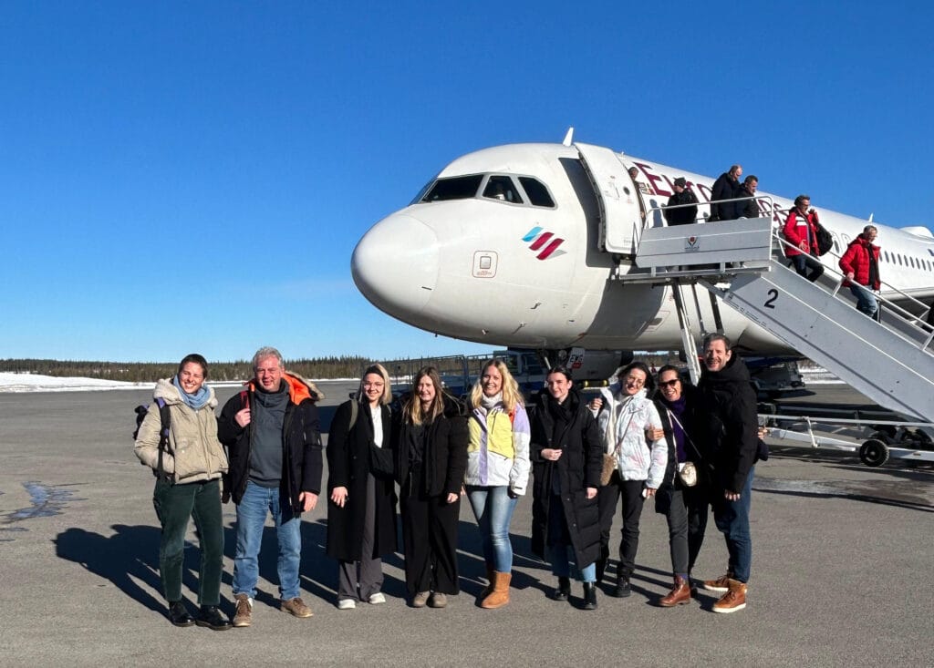 Eine Gruppe von Menschen steht vor einem Eurowings Flugzeug und blickt in die Kamera.